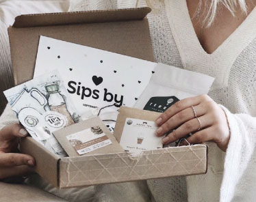 Sips by tea box in woman's hands