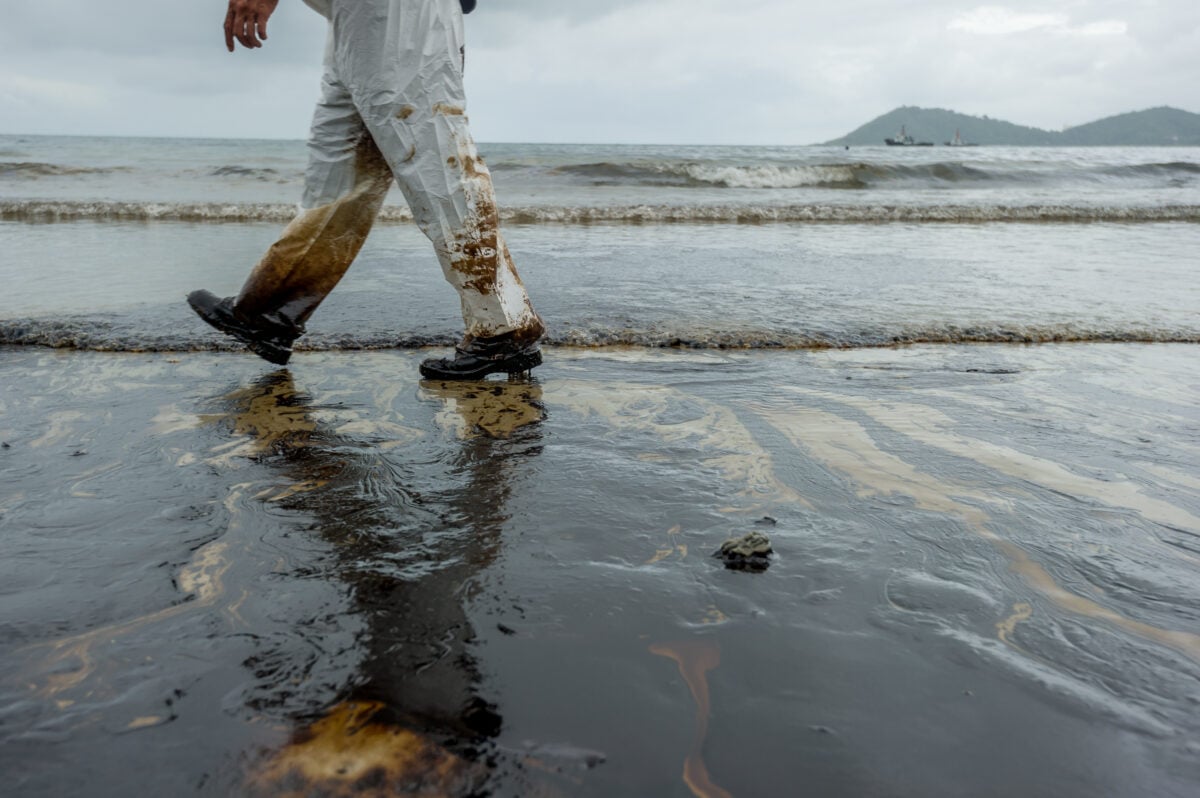 Petroleum spill mixed with other chemical substances on sea and sand surface.