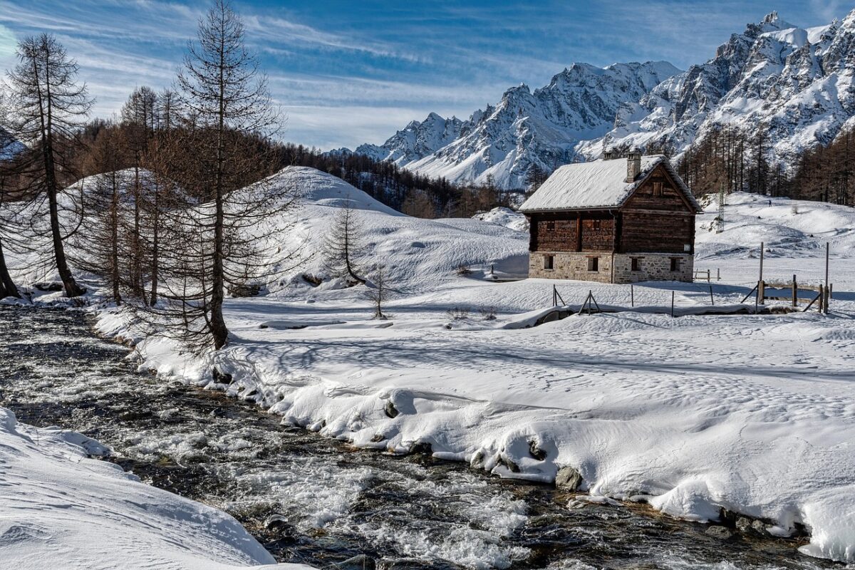 A small wooden cabin next to a frozen river.
