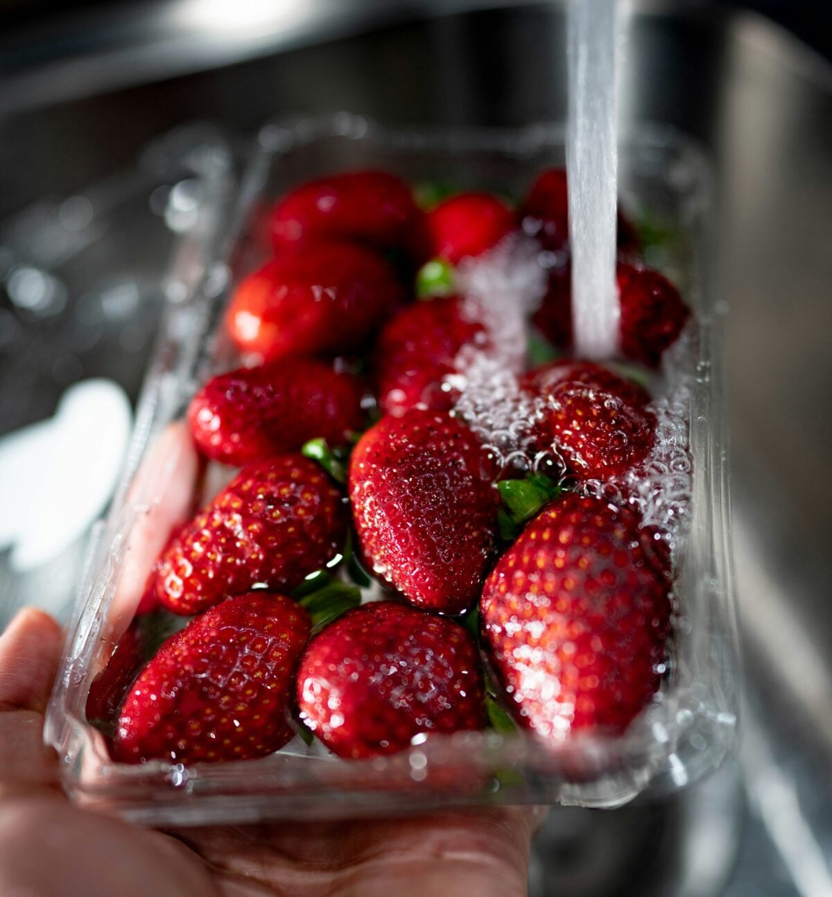 Strawberries being washed in a faucet