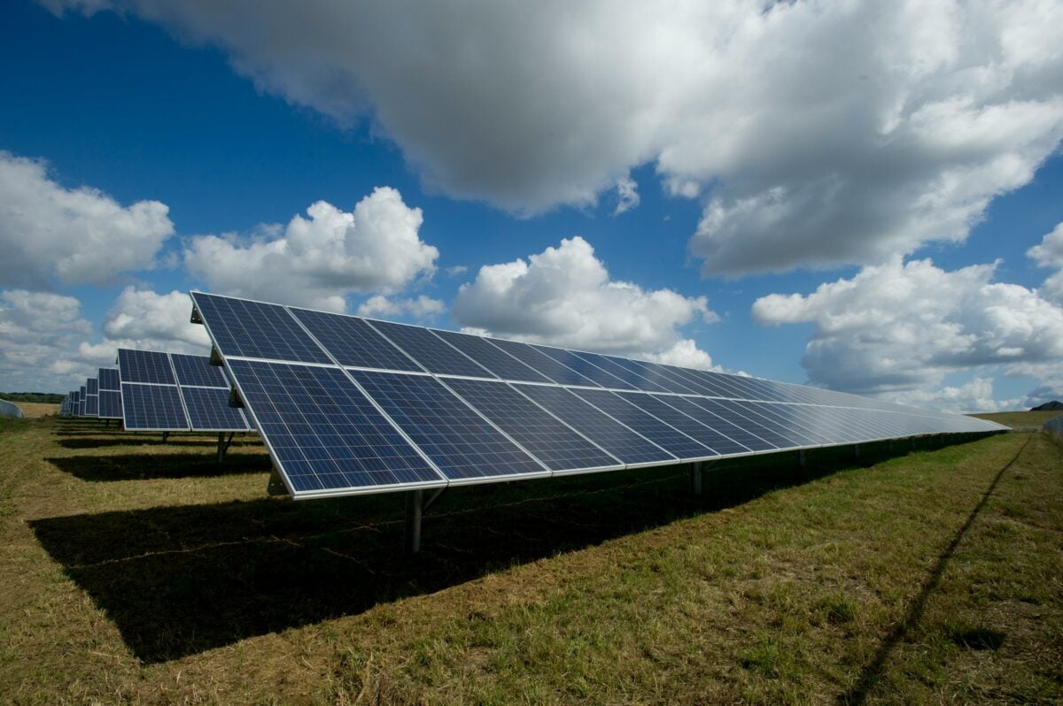 Solar panels in a field with clouds above