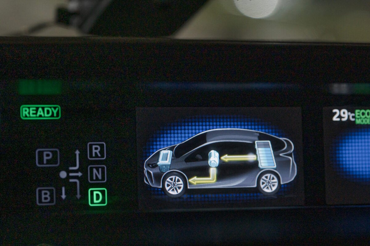 A close-up of a hybrid car's illuminated ready indicator and animated power flow diagram on the dashboard display.