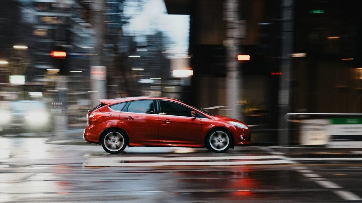 Red prius driving on city streets.