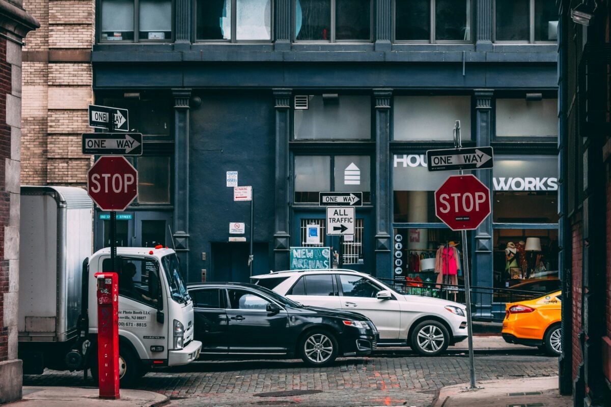 Several vehicles parked near two stop signs.